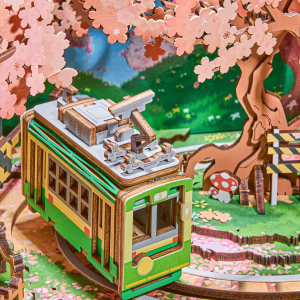 Boîte à musique DIY Rolife Sakura Dreamy Tour AMT02 représentant un tramway miniature japonais sous des cerisiers en fleurs dans un téléviseur rétro.