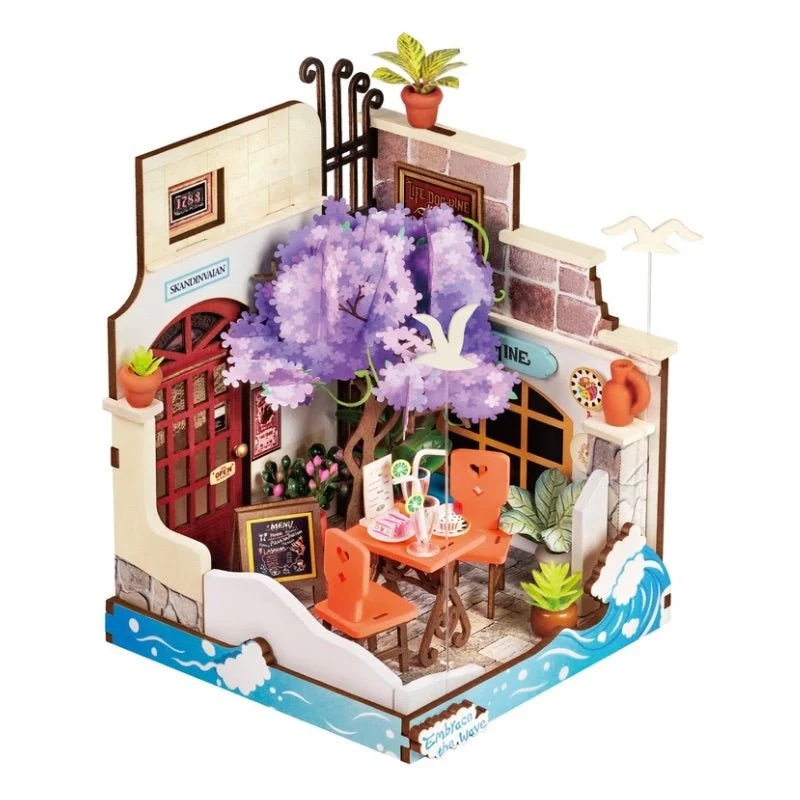 Rolife Sea Holiday Restaurant DS039, maison miniature 3D représentant un restaurant en bord de mer avec arbre fleuri violet, table extérieure orange, plantes, mouettes et vagues bleues.